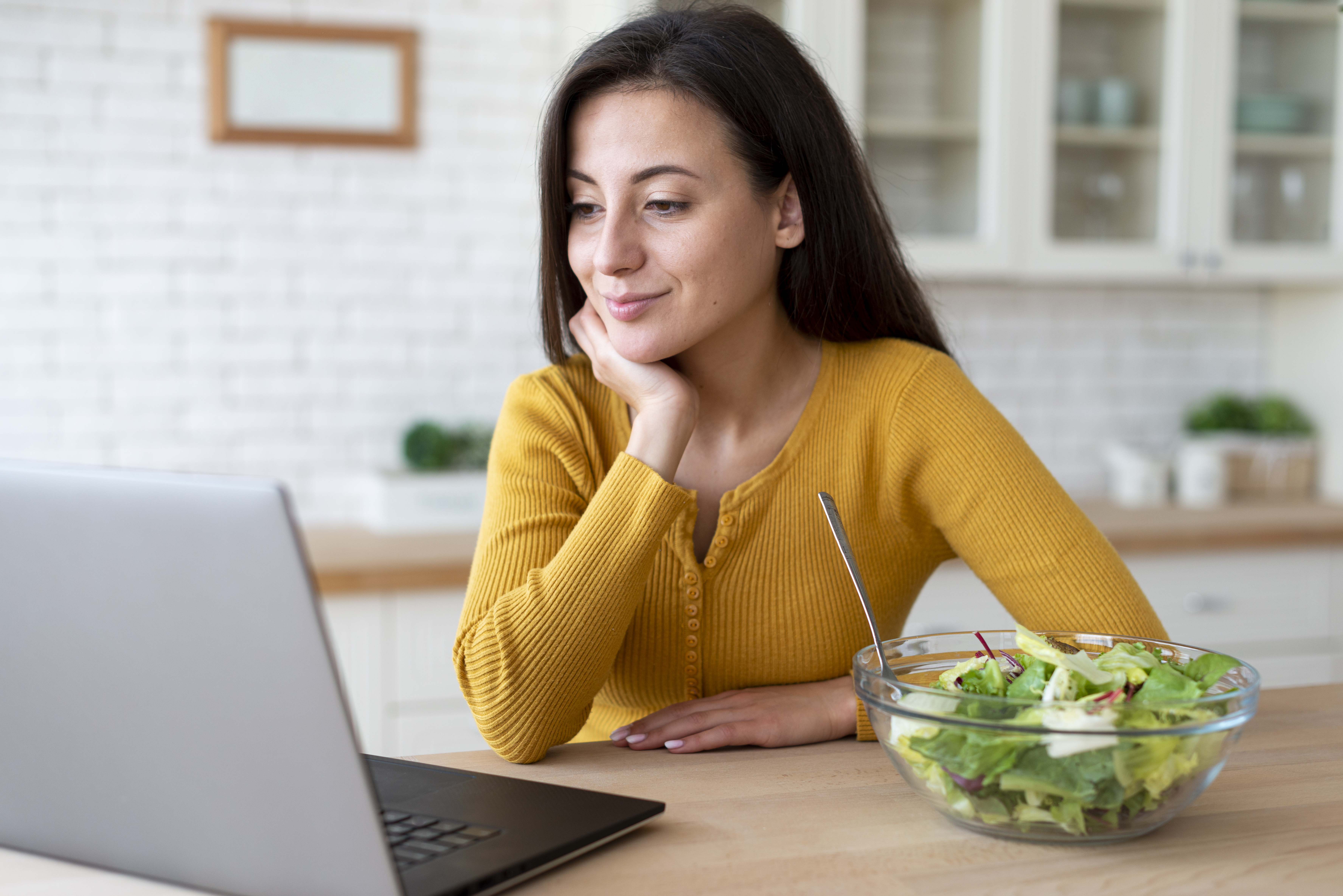 Mulher sorrindo em consulta nutricional online pelo notebook
